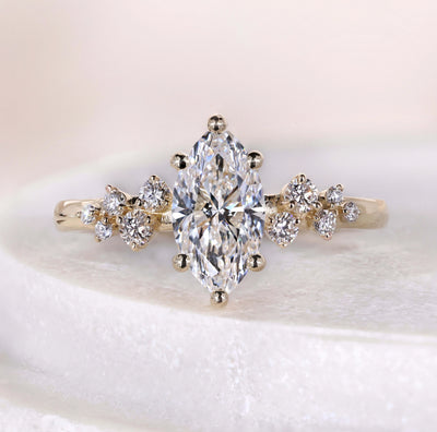 Marquise cut engagement ring with side stones in yellow gold band