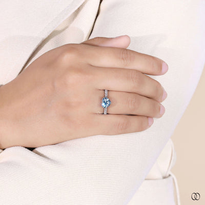 Heart shaped engagement ring with blue diamond and pave band
