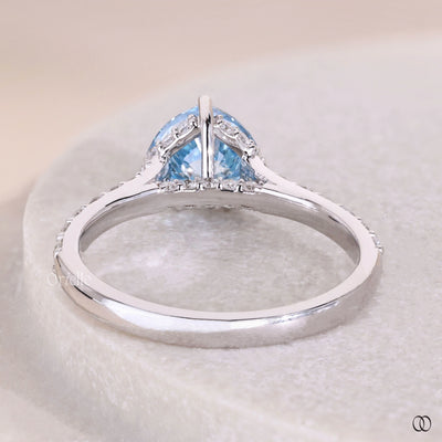 White gold heart shaped engagement ring with blue diamond accent

