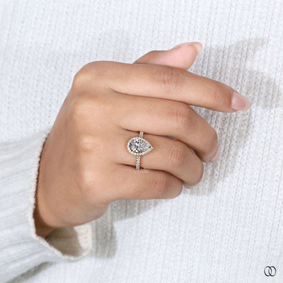 Pear cut engagement ring framed by round diamond halo
